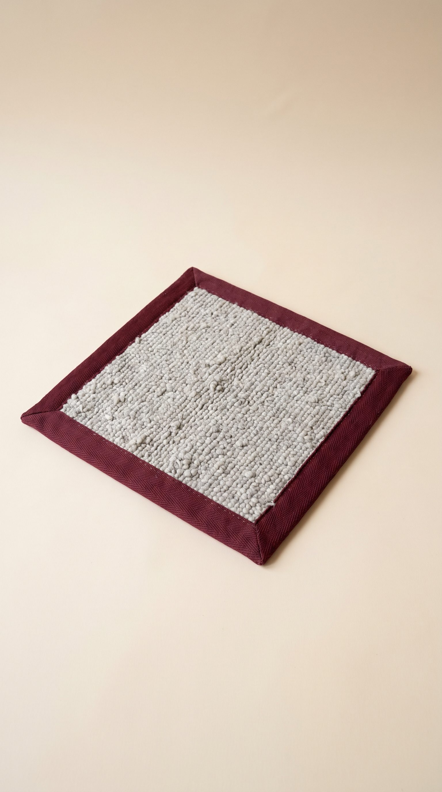 Grey textured rug with a burgundy tape border